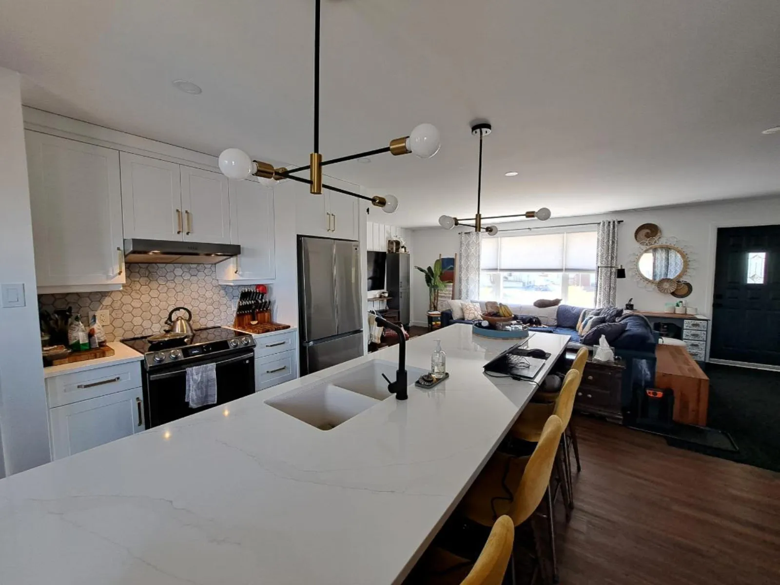 Custom white kitchen remodel with quartz island and brass lighting by Action Construction North Bay